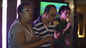 Tres personas cantan en un karaoke